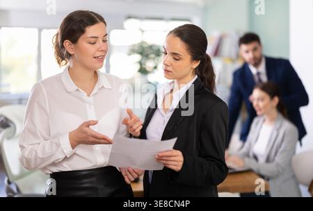 Two qualified female employees discussing work tasks Stock Photo