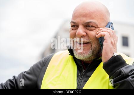 Bearded man communicating with smartphone while standing outdoors Stock Photo