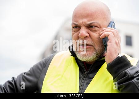 Angry bald man talking on phone, showing frustration and stress Stock Photo