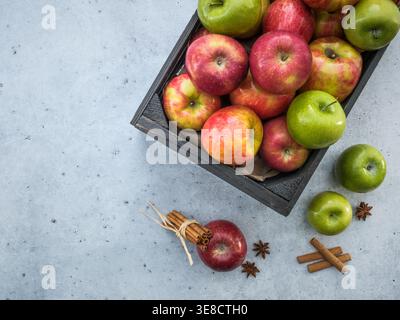 Overhead of black fruit harvest crate box with fresh red and green apples on a neutral light gray counter background. Fall autumn backdrop scene. Copy Stock Photo