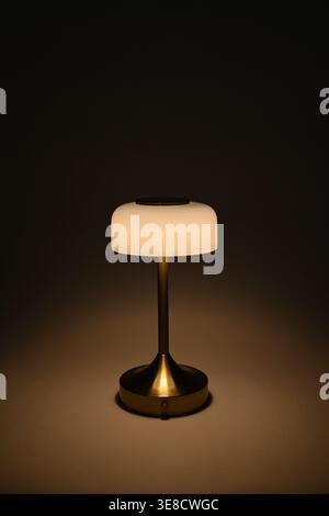 Small white lamp shade on brass lamp post with glowing warm light Stock Photo