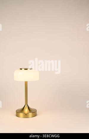 Small white lamp shade on brass lamp post with glowing warm light Stock Photo