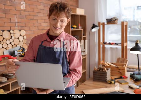 Young carpenter using laptop in workshop Stock Photo