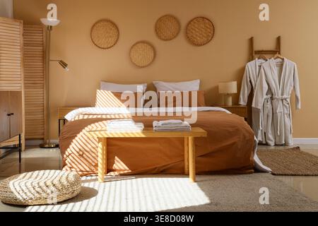 Interior of hotel room with clean linen on bed, bench and bathrobes Stock Photo