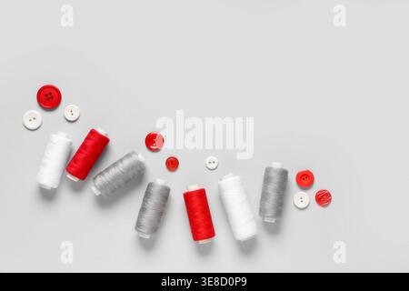 Thread spools with buttons on grey background Stock Photo