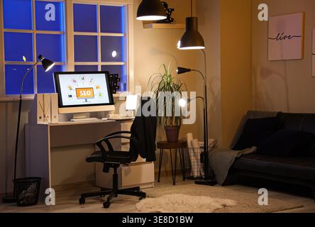 Computer screen with abbreviation SEO in cozy dark office Stock Photo