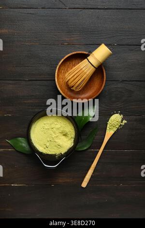 Composition with powdered matcha tea, accessories and plant leaves on dark wooden background Stock Photo