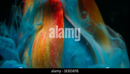 Fog flower. Ethereal smoke. Defocused yellow red color tulip plant nature blue ink flowing in water on abstract dark black background. Stock Photo