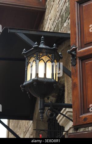 Old lantern hangs on a stone wall near wooden shutters Stock Photo