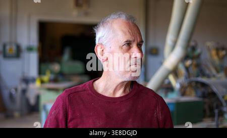 Senior man working as carpenter in workshop looking focused Stock Photo