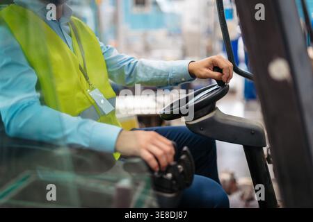 Male factory supervisor driving foklift in industrial production hall. Stock Photo