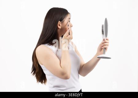 Woman looking in the mirror and touching her face Stock Photo