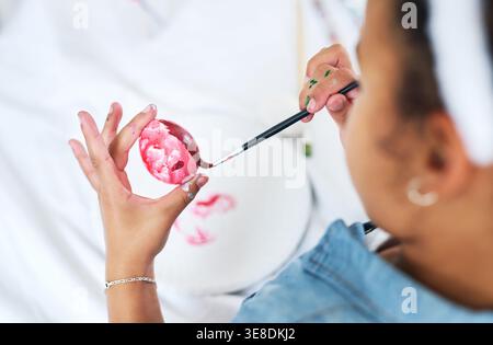 Hands, paintbrush and easter eggs with stroke in home with color, creativity and celebration. Child, above and painting with artwork, pattern and Stock Photo