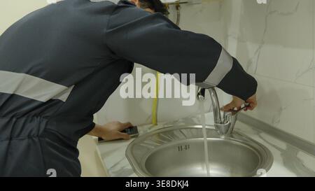 Professional plumber repairing a sink faucet in kitchen Stock Photo