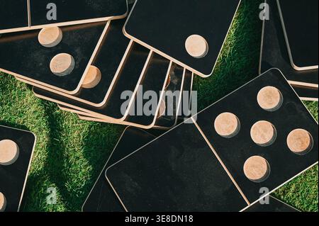 High-angle view of wooden domino-style tiles scattered across green grass. Ideal for outdoor recreation themes, summer leisure, teamwork concepts, and Stock Photo