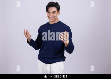 Laughing man in blue sweatshirt with open arms in studio Stock Photo