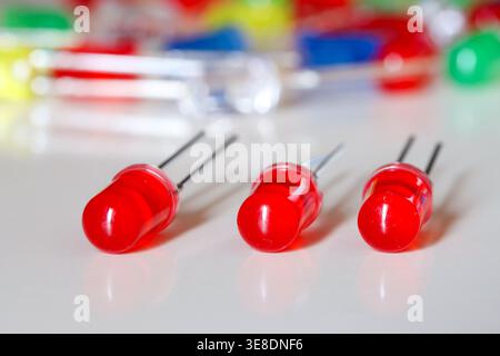 Red LED diodes aligned on white background with colorful blurred electronics Stock Photo