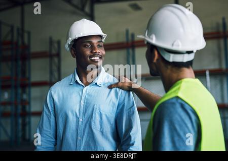 Businessmen, contractor and conversation with team in warehouse for storage safety or distribution. Male people, employees or engineers with smile for Stock Photo