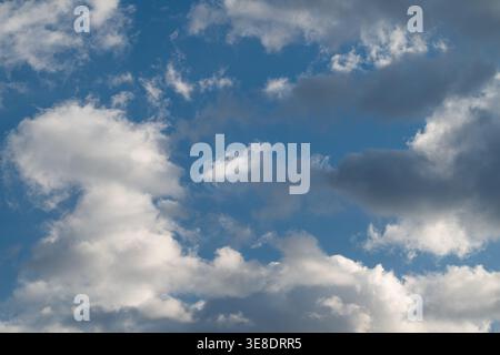 Turbulent clouds over shifting blue sky, dramatic contrasts and dynamic movement suggesting incoming storm, weather forecast, climate narrative Stock Photo