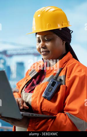 Offshore platform specialist managing maintenance systems with laptop, scheduling gear repairs. African american engineer overseeing mechanical and structural integrity of drilling rig with notebook Stock Photo