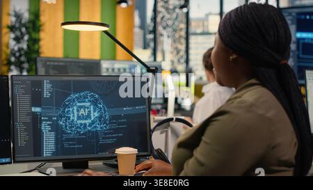 System administrators in startup office work with artificial intelligence driving market innovation. Tech agency IT specialists brainstorming to apply deep learning optimizing operations, camera B Stock Photo