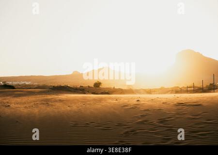Textured sand ripples in UAE desert with golden sunset and distant mountains Stock Photo