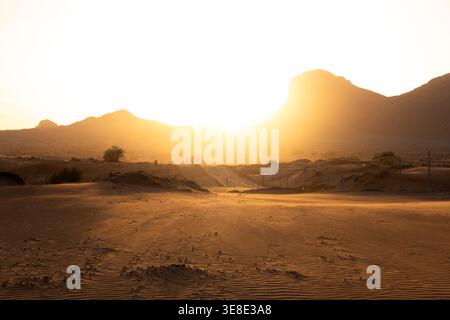 Natural sand dune patterns with sunset over mountains in Oman desert Stock Photo