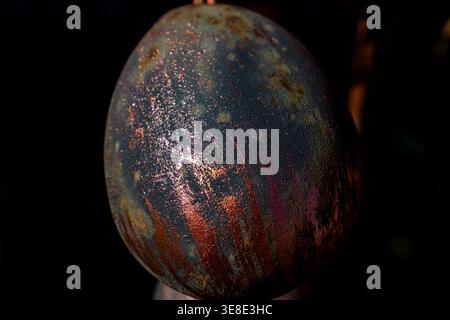 Detailed view of the underside of a metal object featuring iridescent copper and purple textures reflecting light against a dark background Stock Photo