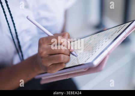 Close up of hand using stylus on tablet with digital planner interface. Schedule management, note taking, online organization, remote work, data entry Stock Photo