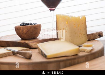 Assorted cheeses, black olives, and wine on wooden boards for tasting Stock Photo