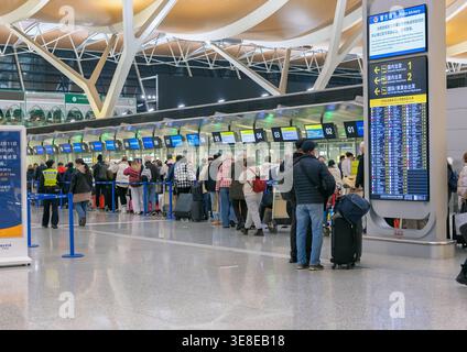 Shanghai, China - December 11, 2025: Passengers waiting in long queue at check-in counters in Pudong International Airport Stock Photo