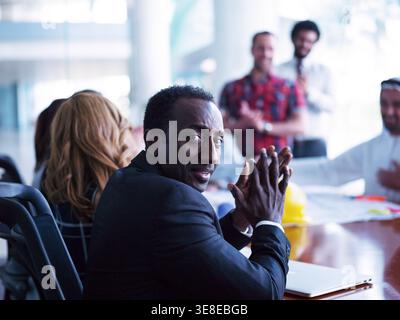 Middle Eastern corporate leader in a diverse startup business meeting with team applauding and collaborating Stock Photo