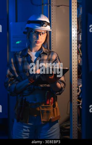 Electrical specialist using tablet near industrial switchboard panel. Technical inspection. Stock Photo