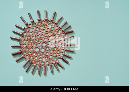 Industrial bolts and nuts arranged in circular composition with empty space on mint background Stock Photo
