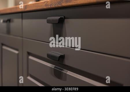 Close up kitchen drawers with black handles. Modern furniture design. Stock Photo