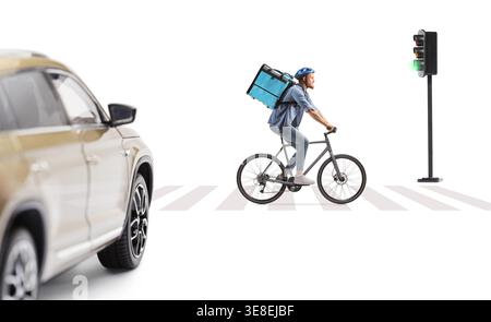 Delivery man riding a bicycle on a pedestrian crossing in front of a car isolated on white background Stock Photo