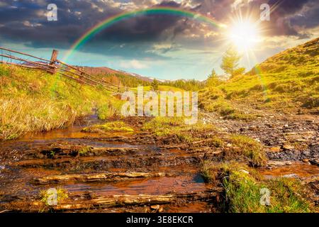 sunset over rural scenery in carpathian mountains. simple view of a countryside mountain landscape during springtime. brook near the grassy hills. wea Stock Photo