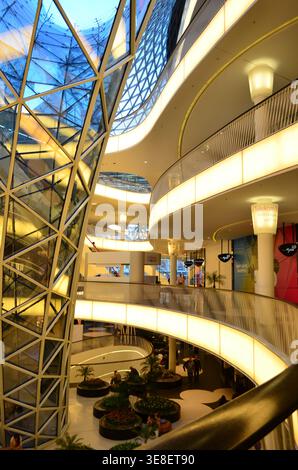 Modern shopping mall interior featuring a striking glass roof and illuminated curved walkways Stock Photo