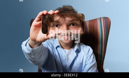 Young man close up holding smartphone frame focusing on eyes studio digital portrait Stock Photo