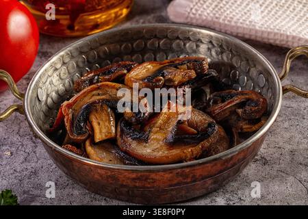 A savory dish of sauteed mushrooms served in a rustic hammered copper bowl. This closeup highlights the warm brown colors delicious texture against a Stock Photo