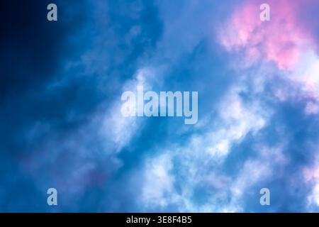 Dramatic sky full of dark clouds in bad weather before a big storm rain with a patch of light blue sky in center. Light emission from the Edge of Stock Photo
