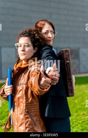 Businesswomen showing thumbs up sharing professional partnership success Stock Photo