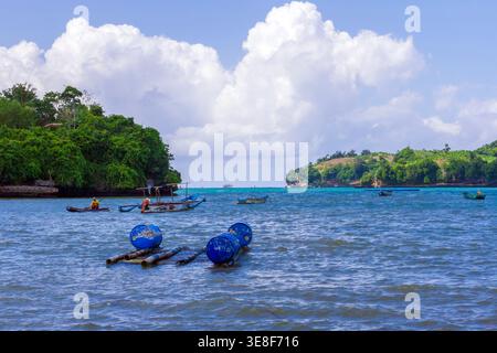 A wide seascape featuring floating fish farm rafts and traditional outriggers in a calm bay surrounded by lush green islands under a cloudy sky. Stock Photo