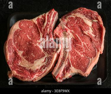 Fresh rib eyed steaks on a black background. Stock Photo