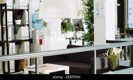 Company department open space with desks, computers at workstations used for business tasks in urban building. Empty startup office with tools and supplies, open floor agency. Stock Photo