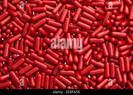 Large group of shiny red pharmaceutical capsules. Large top view. Stock Photo