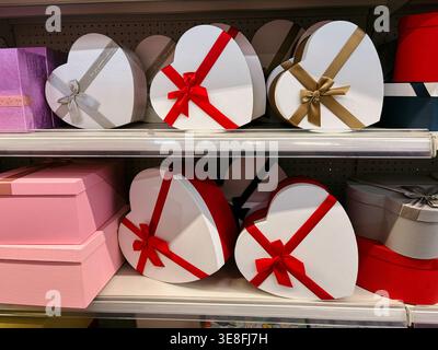 Heart shaped gift boxes with ribbons displayed on store shelf. Concept of love, romance and holiday gifting. Stock Photo