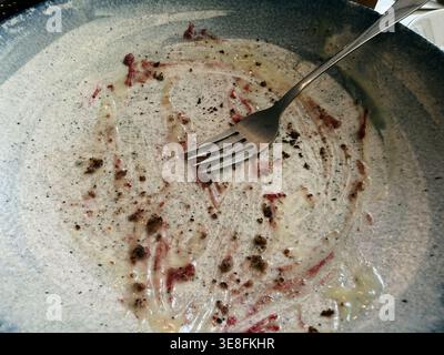 Empty plate with crumbs and sauce after eating dessert. Concept of satisfaction, finished meal and food enjoyment. Stock Photo