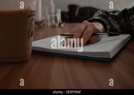 Close-up of Hand Writing in Notebook with Coffee Stock Photo
