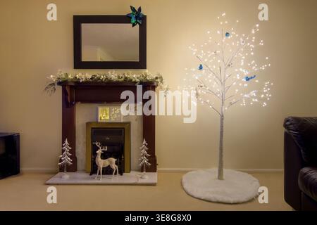 Minimalist Christmas living room with lit decorative tree, fireplace and festive decorations in a calm modern home interior Stock Photo
